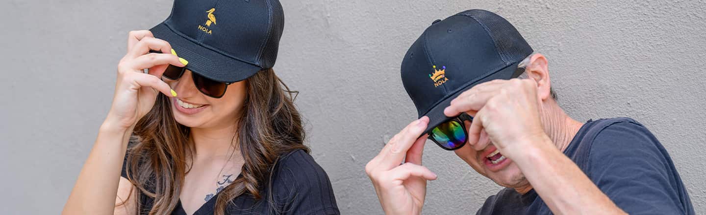Man and woman touching their hats.